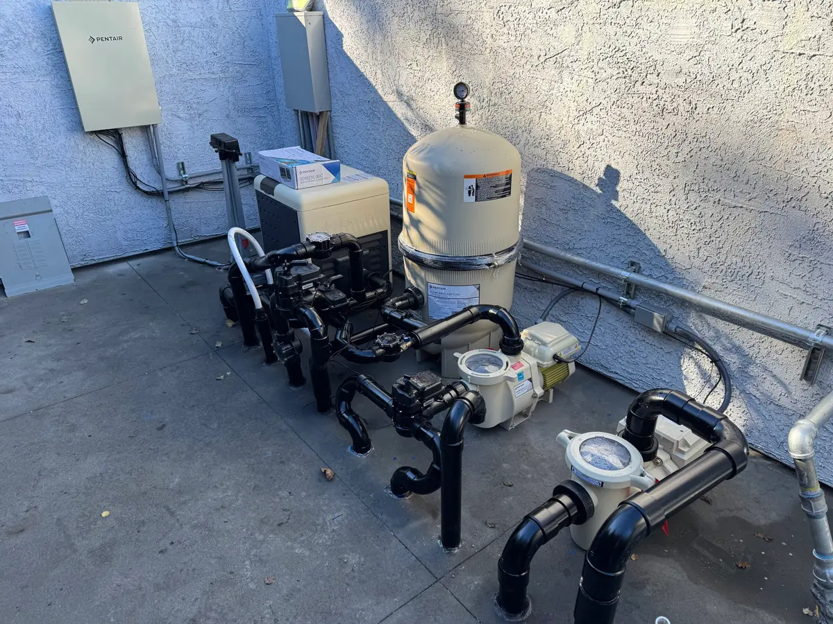 Pool pumps, filter and plumbing on an equipment pad.